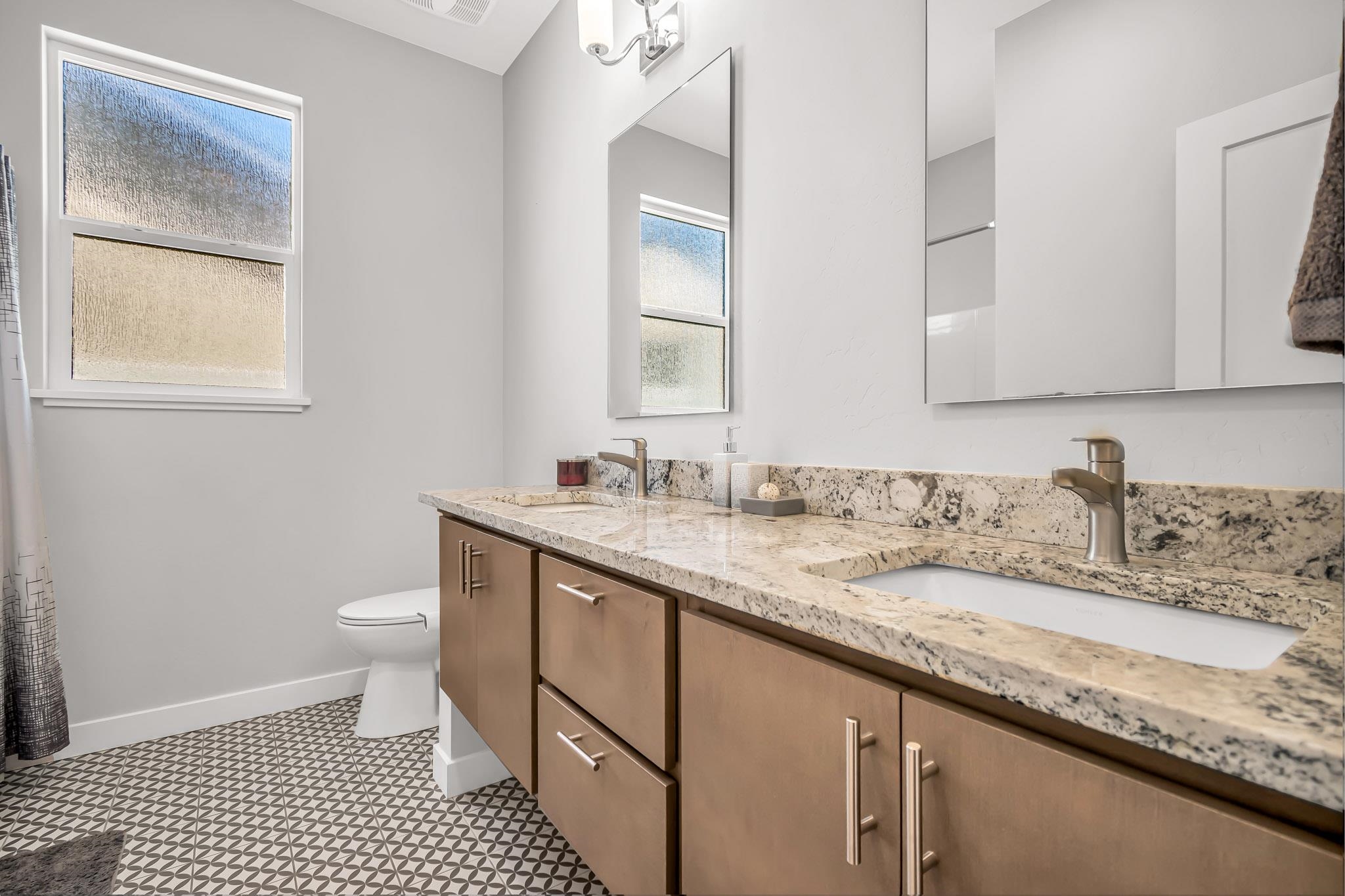 506 Grama Court Grand Junction, CO 81504 - Photo 22 of 28 a bathroom with a granite countertop sink a toilet and a mirror