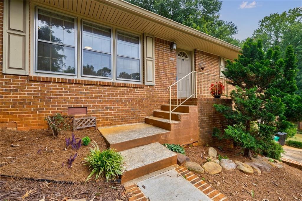 3268 East Castle Court Decatur, GA 30033 - Photo 1 of 1 a brick building with a bench and a potted plant