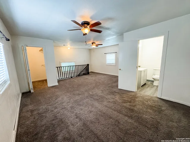 en empty room with windows and ceiling fan