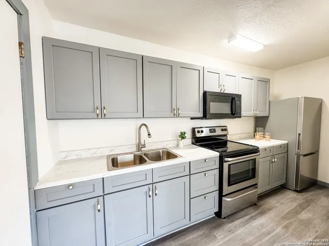 a kitchen with a sink white cabinets and stainless steel appliances