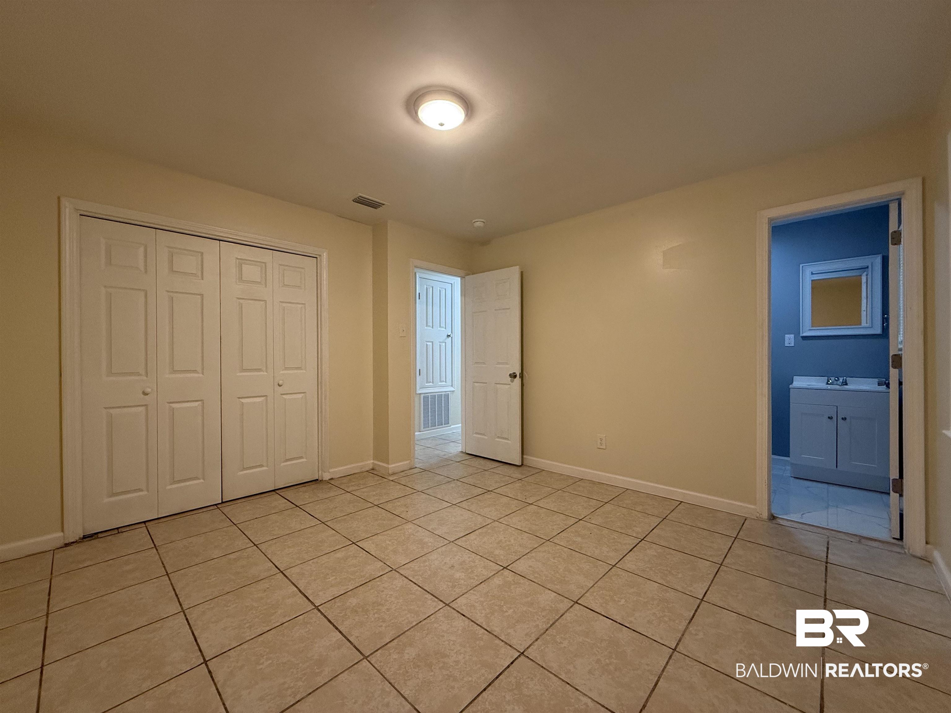 320 E Street Prichard, AL 36610 - Photo 11 of 16 Unfurnished bedroom featuring light tile patterned flooring, ensuite bathroom, sink, and a closet
