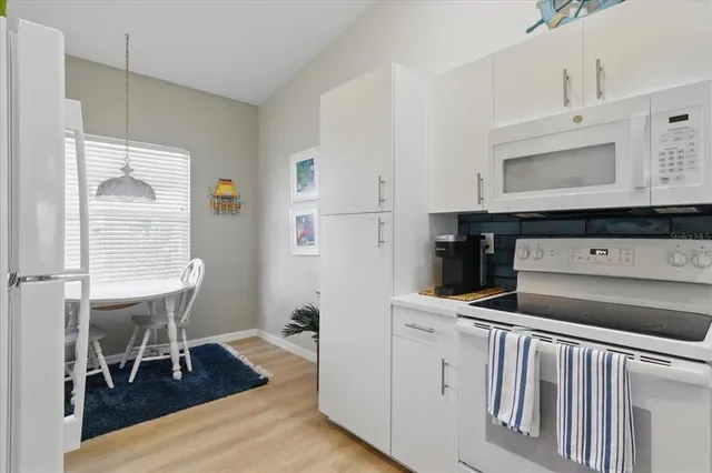 a kitchen with white cabinets and appliances