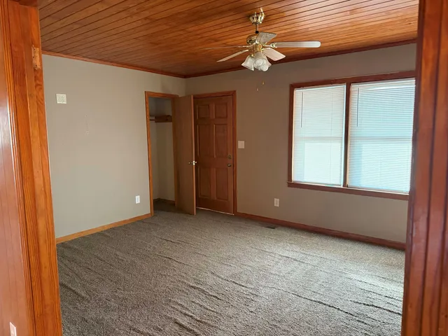 an empty room with chandelier fan and windows