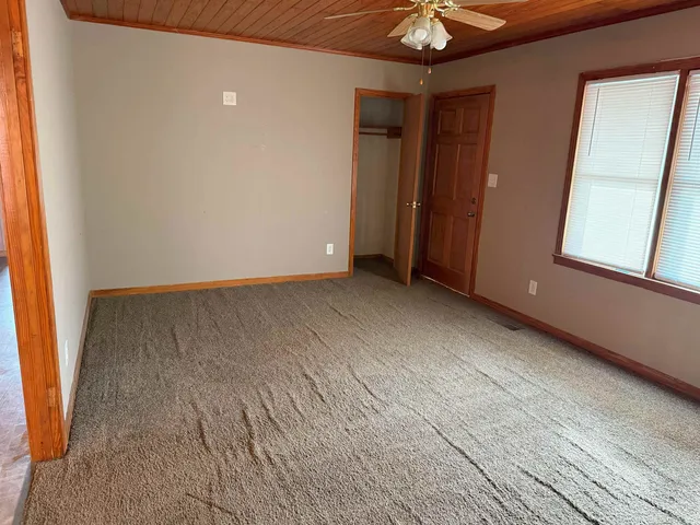 an empty room with chandelier fan and windows
