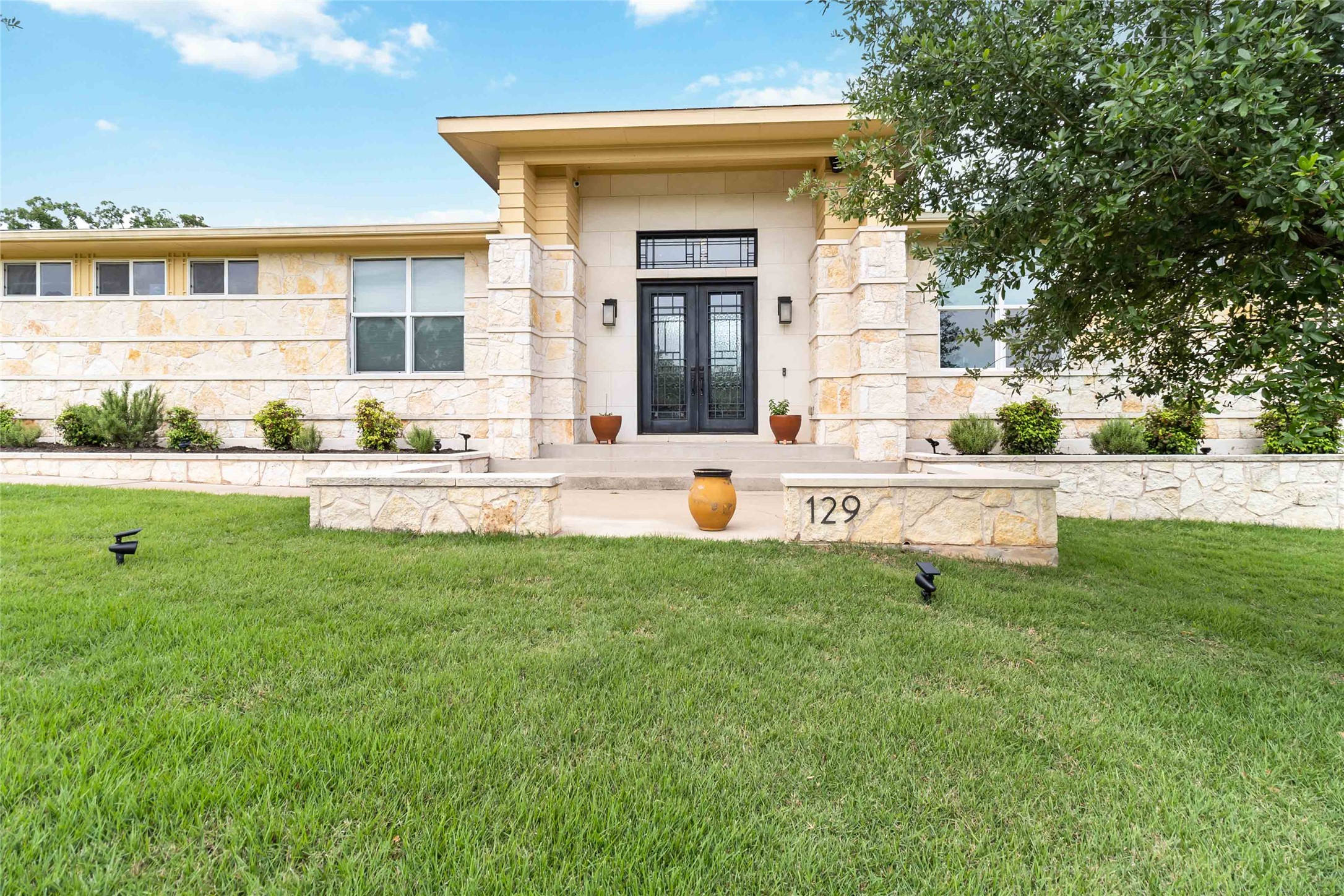 Entrance to property with a lawn, stone siding, and french doors