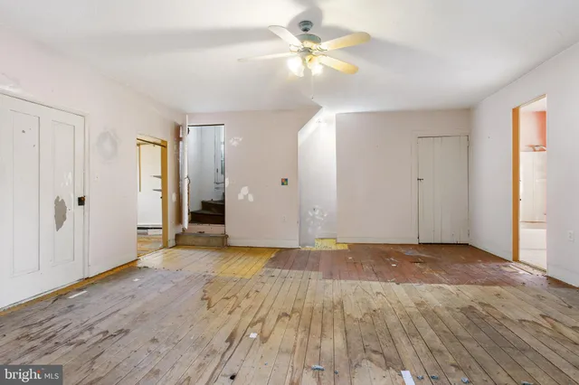 an empty room with wooden floor and a ceiling fan