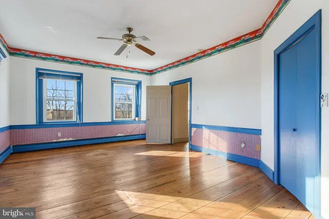 a view of empty room with wooden floor and fan