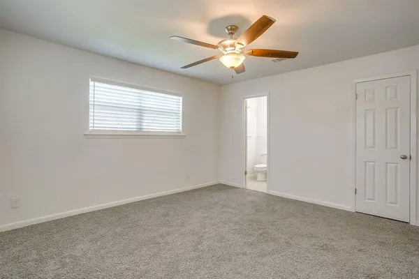 an empty room with closet and a ceiling fan