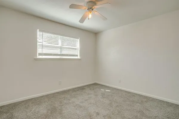 an empty room with a chandelier fan and closet area