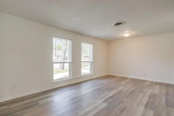 a view of an empty room with wooden floor and a window