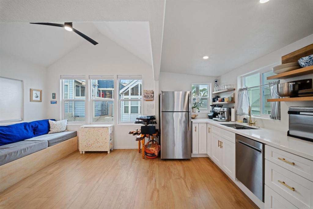 a kitchen with stainless steel appliances granite countertop a refrigerator a stove a sink dishwasher and white cabinets with wooden floor