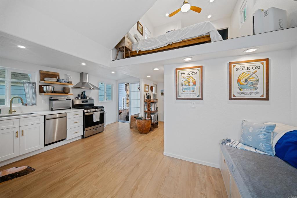 1624 North Coast Highway 101, Unit 45 Encinitas, CA 92024 - Photo 13 of 37 a kitchen with stainless steel appliances kitchen island granite countertop a refrigerator a sink a stove and white cabinets with wooden floor