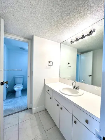 a spacious bathroom with a granite countertop sink a toilet and a mirror