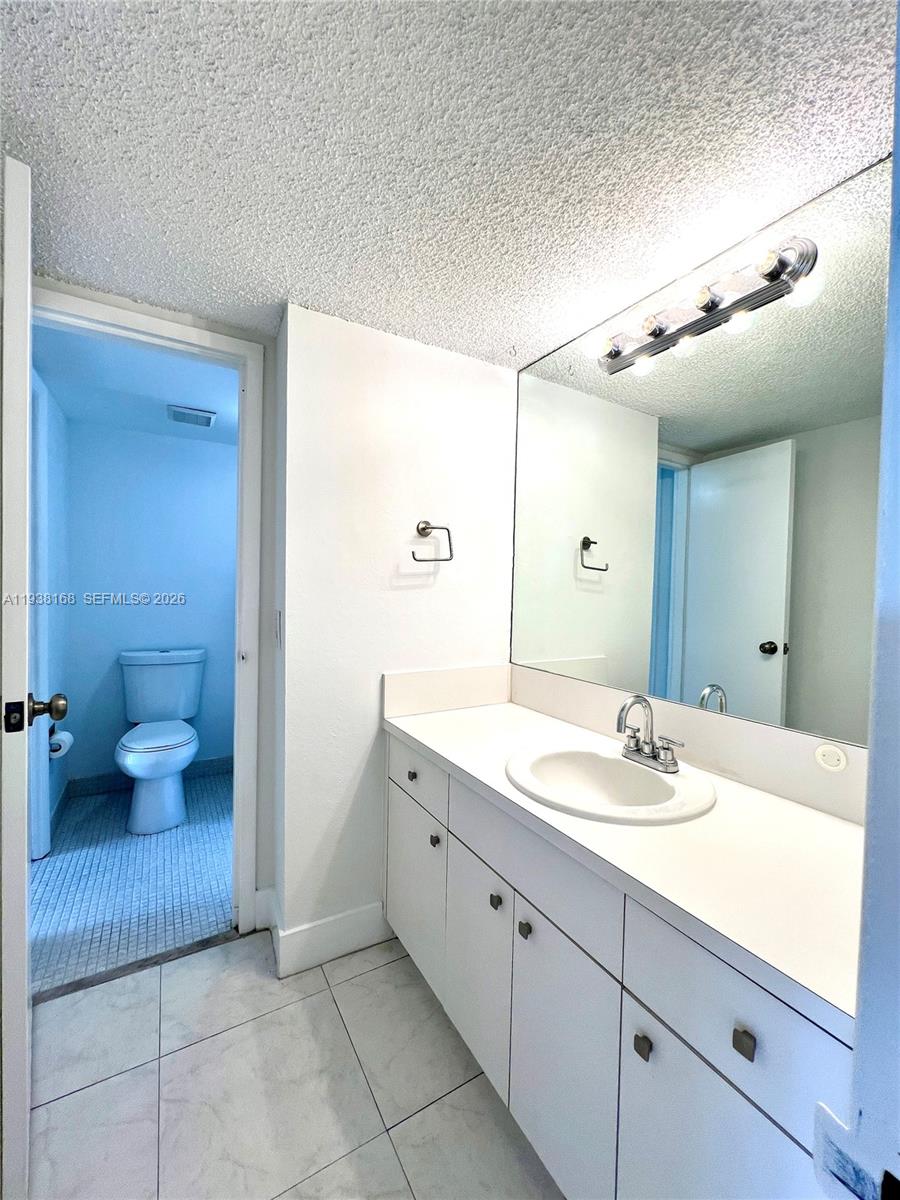 2160 Southwest 16th Avenue, Unit 314 Miami, FL 33145 - Photo 13 of 15 a spacious bathroom with a granite countertop sink a toilet and a mirror