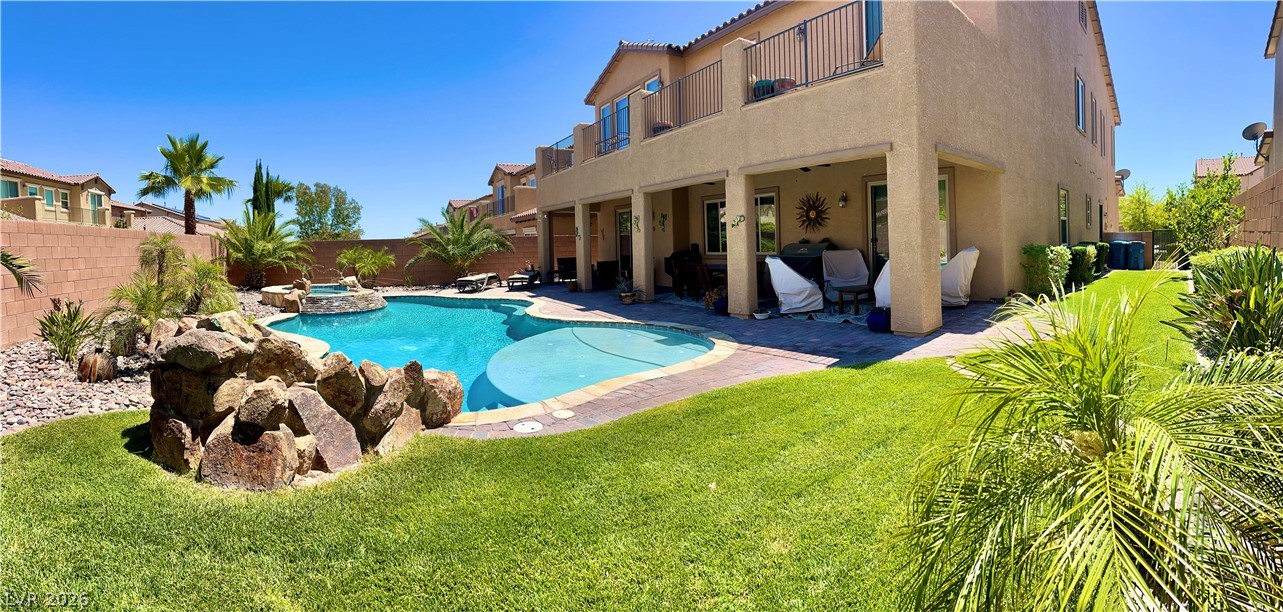 9724 University Ridge Avenue Las Vegas, NV 89149 - Photo 24 of 61 An inviting backyard oasis offers a sparkling in-ground pool with an integrated spa, set amidst lush green lawn and mature landscaping.