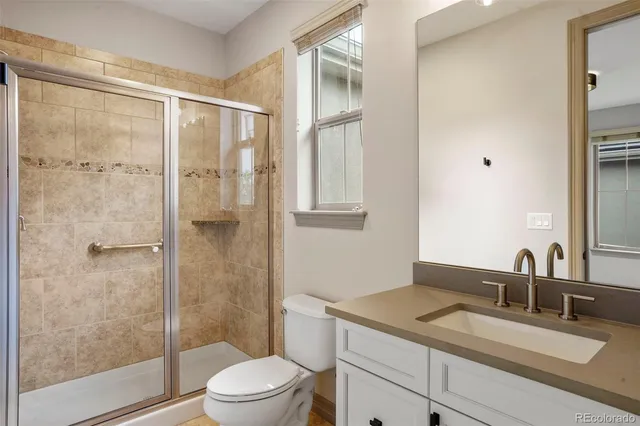 a bathroom with a granite countertop sink toilet a mirror and shower