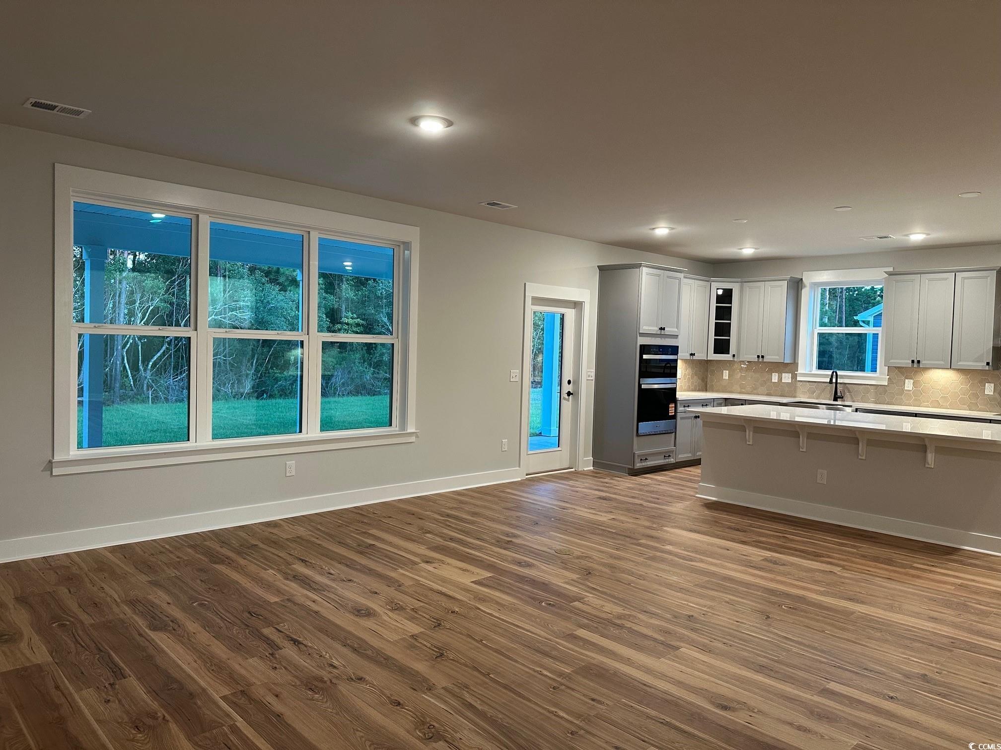 85 Northbrook Drive Murrells Inlet, SC 29576 - Photo 11 of 34 Kitchen with decorative backsplash, a breakfast bar area, dark wood-style floors, glass insert cabinets, and recessed lighting