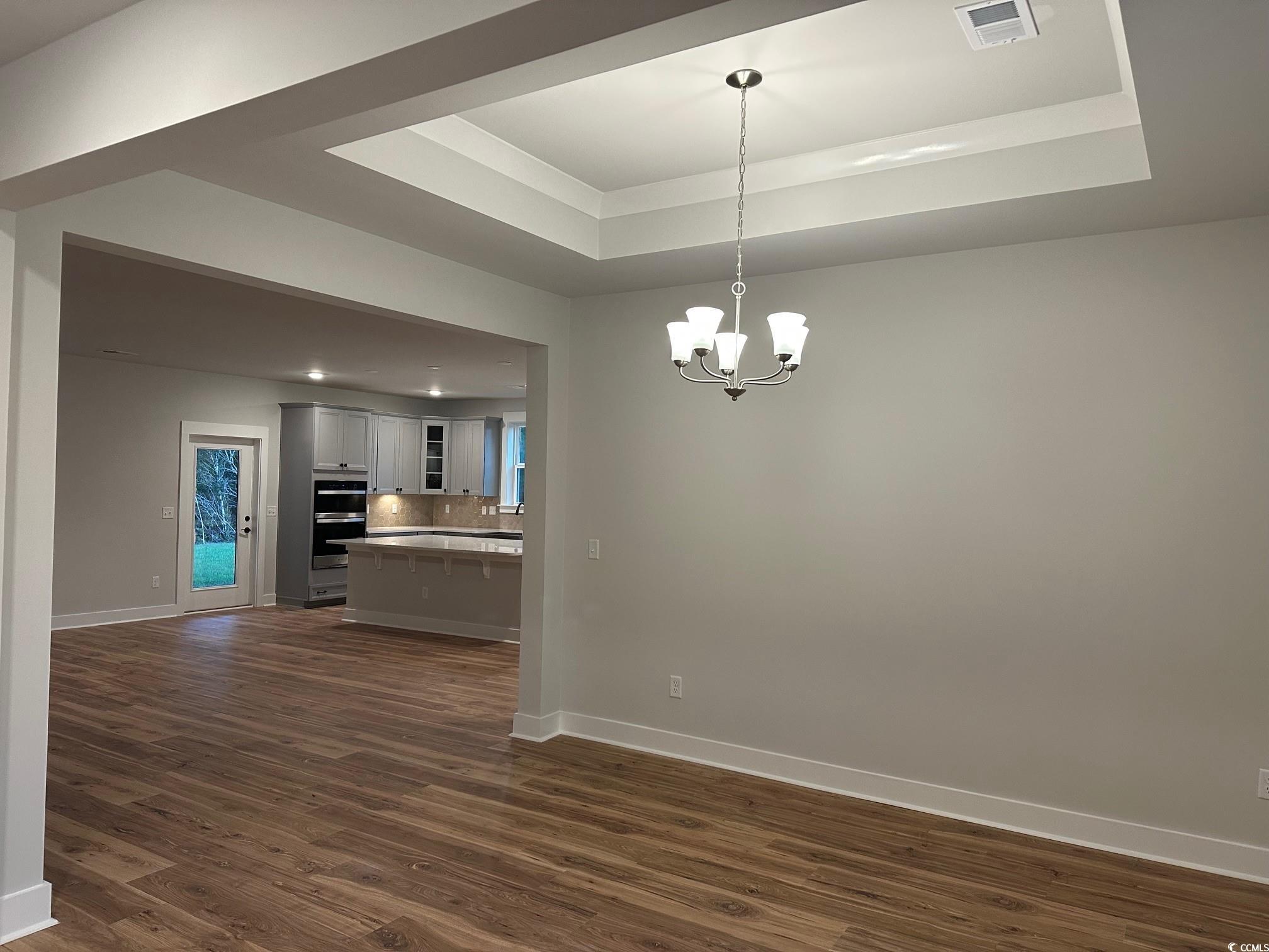 85 Northbrook Drive Murrells Inlet, SC 29576 - Photo 6 of 34 Unfurnished dining area featuring a raised ceiling, dark wood-type flooring, and a chandelier