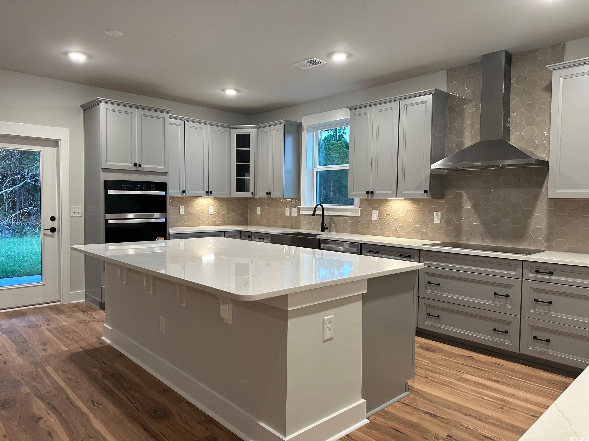 85 Northbrook Drive Murrells Inlet, SC 29576 - Photo 7 of 34 Kitchen with gray cabinets, wall chimney range hood, light stone counters, decorative backsplash, and recessed lighting