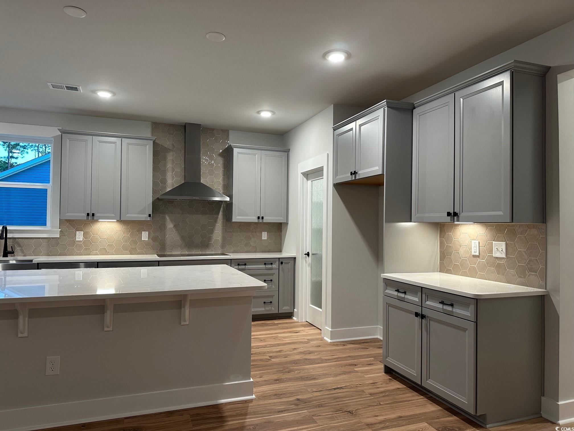 85 Northbrook Drive Murrells Inlet, SC 29576 - Photo 8 of 34 Kitchen with gray cabinets, backsplash, wall chimney range hood, light stone counters, and recessed lighting