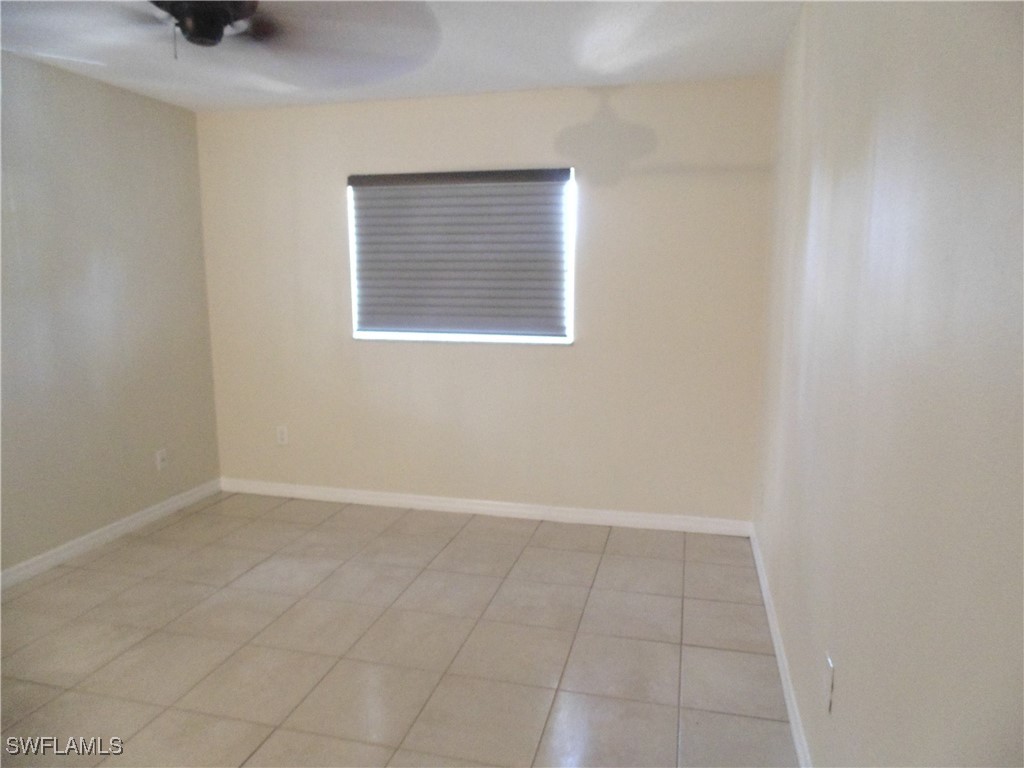 18215 Iris Road Fort Myers, FL 33967 - Photo 10 of 34 an empty room with a white cabinet a window and a ceiling fan