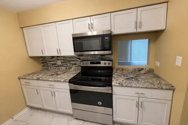 a kitchen with granite countertop a stove microwave and sink