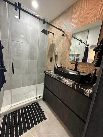 a bathroom with a glass door shower a mirror and a sink