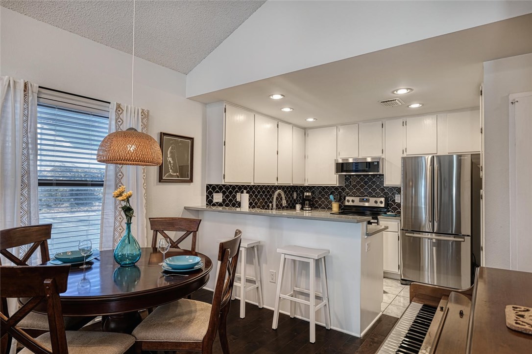 1748 Ohlen Road, Unit 74 Austin, TX 78757 - Photo 5 of 15 a kitchen with stainless steel appliances granite countertop a stove refrigerator a table and chairs