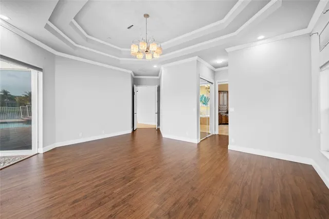 a view of an empty room with wooden floor and a chandelier