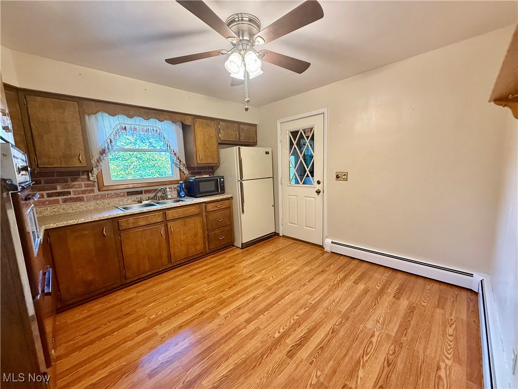4878 Wylie Ridge Road New Cumberland, WV 26047 - Photo 6 of 20 Kitchen with light countertops, brown cabinets, light wood-style floors, freestanding refrigerator, and a baseboard heating unit