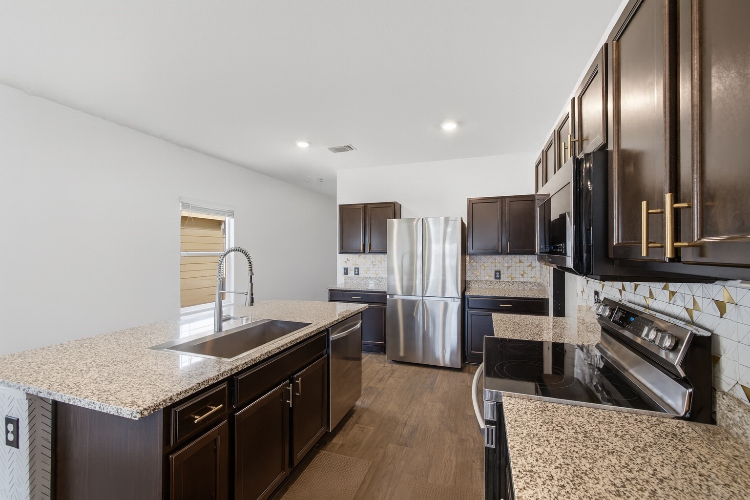 15000 Bajada Rd Manor Manor, TX 78653 - Photo 10 of 31 A well-appointed kitchen showcasing dark cabinetry, granite countertops, and modern stainless steel appliances.