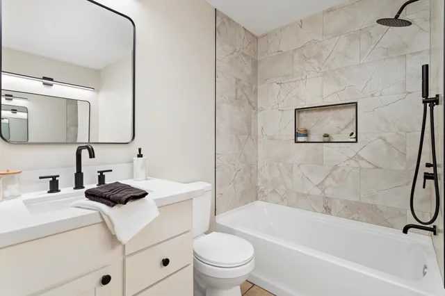 a bathroom with a granite countertop sink a toilet and a bathtub