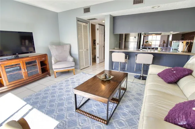 a living room with furniture a flat screen tv and kitchen view