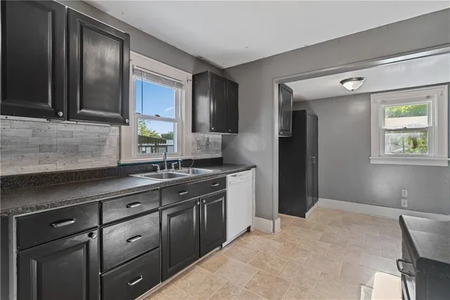a kitchen with granite countertop a sink cabinets and stainless steel appliances
