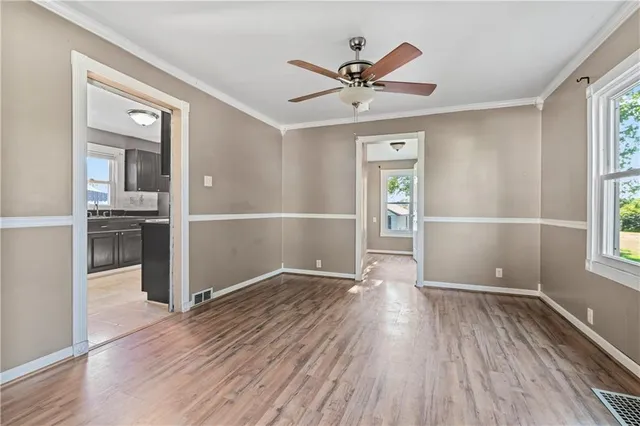 an empty room with wooden floor closet and windows