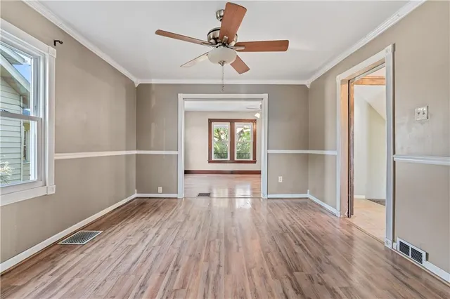 a view of empty room with wooden floor and fan