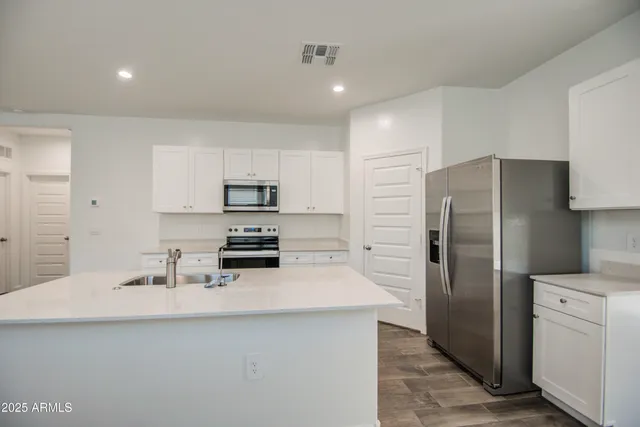 a kitchen with a refrigerator sink and white cabinets