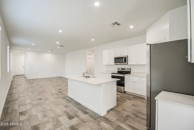 a kitchen with stainless steel appliances kitchen island sink refrigerator and microwave