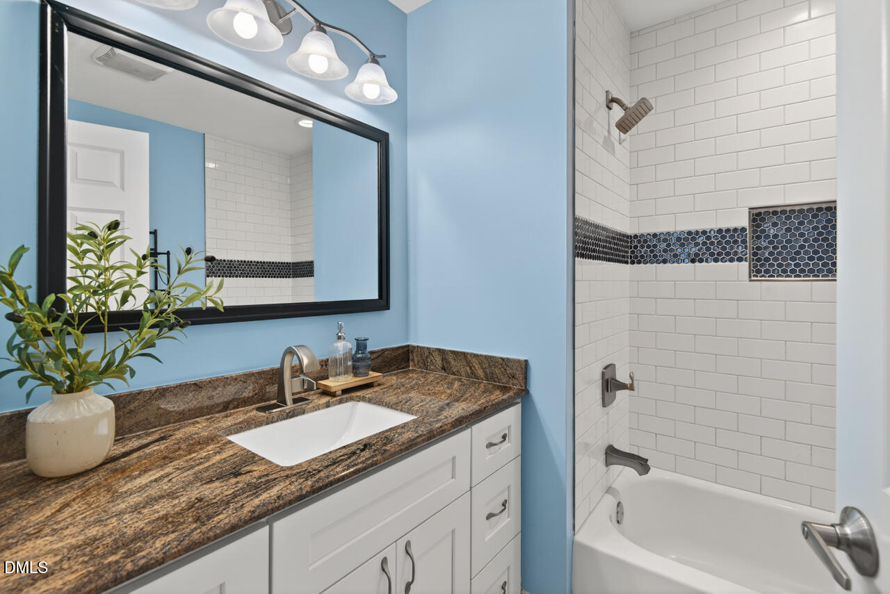 802 Cox Avenue Durham, NC 27701 - Photo 30 of 41 a bathroom with a granite countertop sink a large mirror and a bathtub