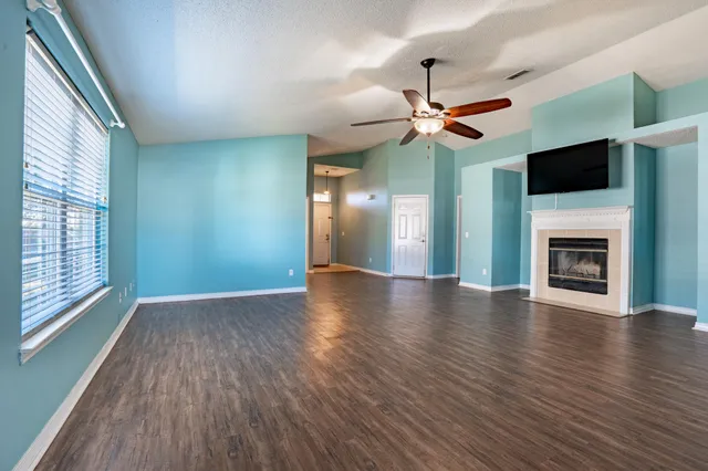 a view of an empty room with window and wooden floor