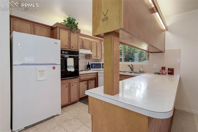 68 Louis Nelson Road Pueblo, CO 81001 - Photo 23 of 38 Kitchen with light tile patterned flooring, sink, kitchen peninsula, white appliances, and backsplash