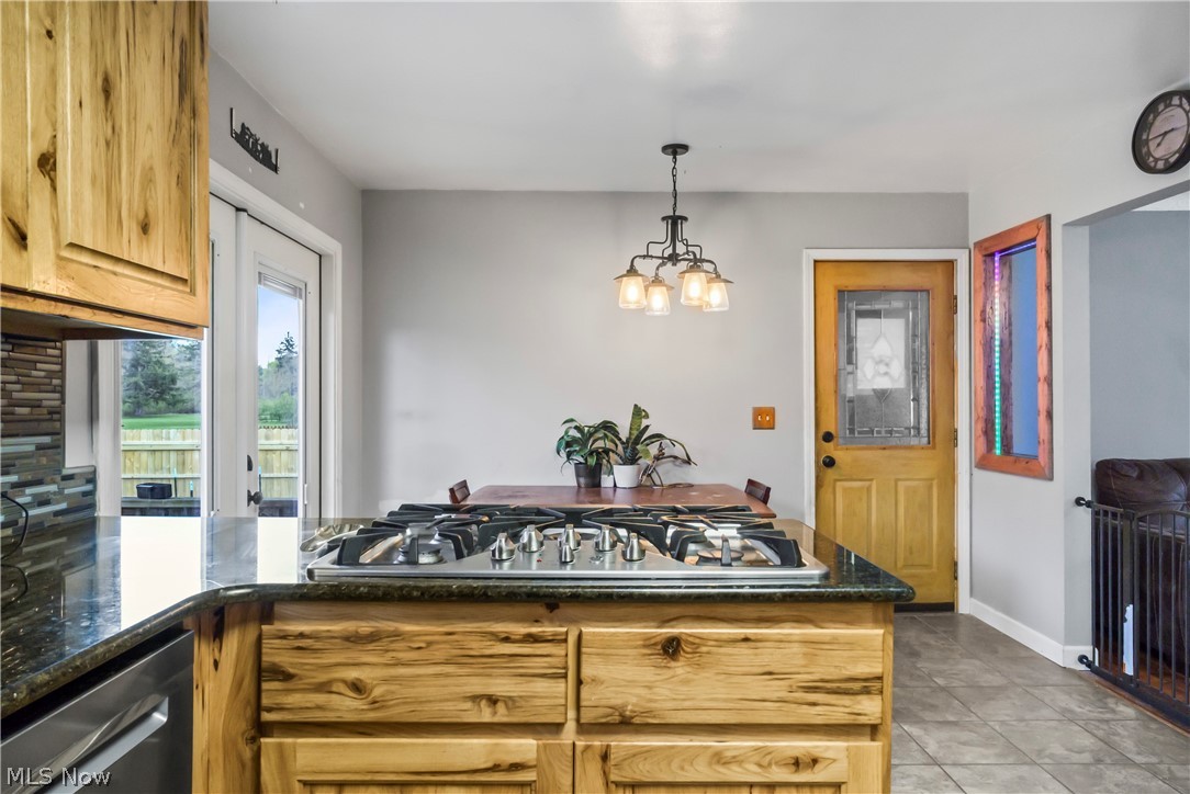 346 Amboy Road Conneaut, OH 44030 - Photo 15 of 41 Kitchen featuring light tile floors, decorative light fixtures, appliances with stainless steel finishes, dark stone countertops, and a chandelier