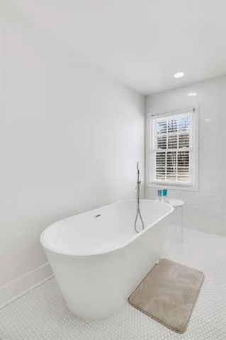 a white bath tub sitting in a bathroom next to a window