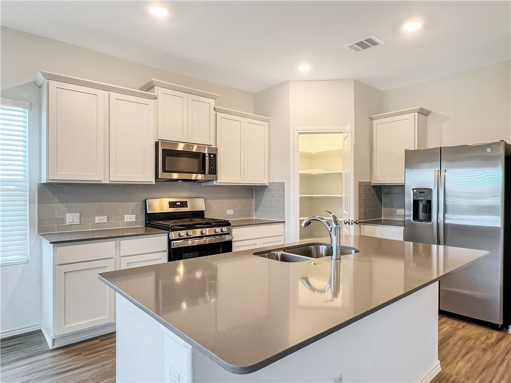 a kitchen with stainless steel appliances granite countertop a sink a stove and microwave