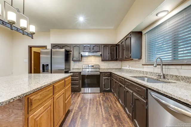 a kitchen with stainless steel appliances granite countertop a sink stove and refrigerator
