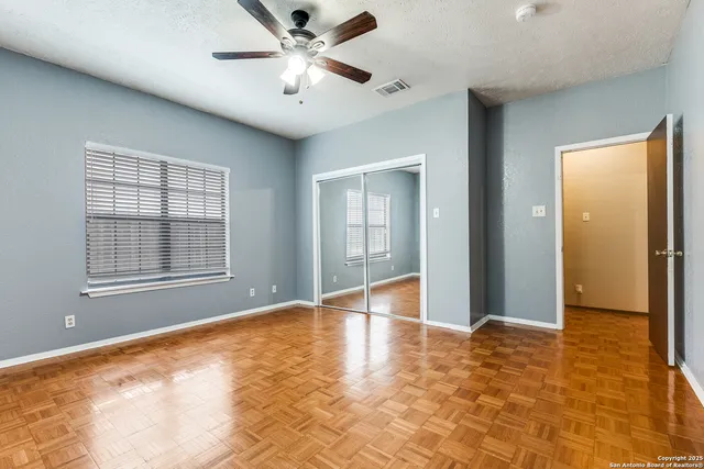 a view of an empty room with window and chandelier fan