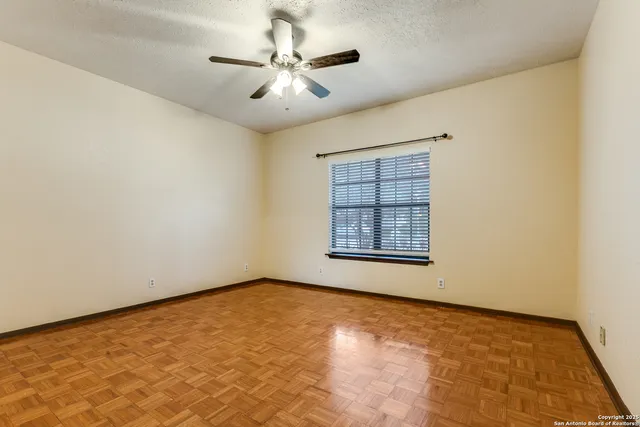 an empty room with a chandelier fan and windows