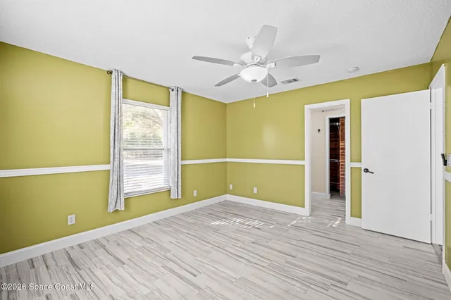 a view of empty room with wooden floor and fan