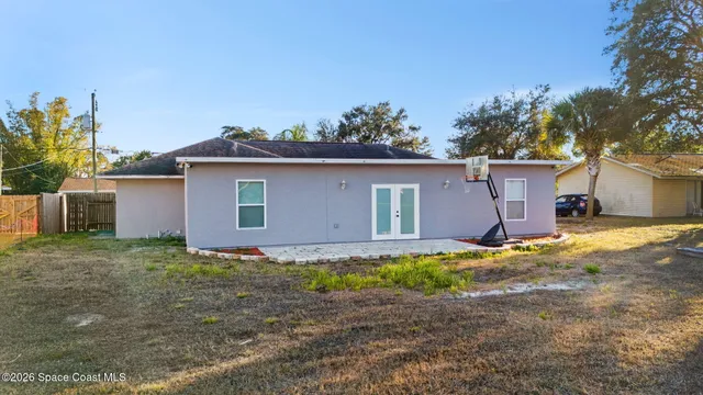 a backyard of a house with plants and large tree