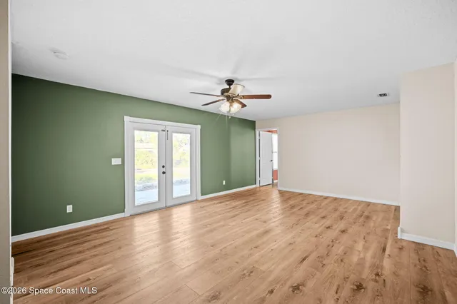 a view of a room with window a ceiling fan and wooden floor